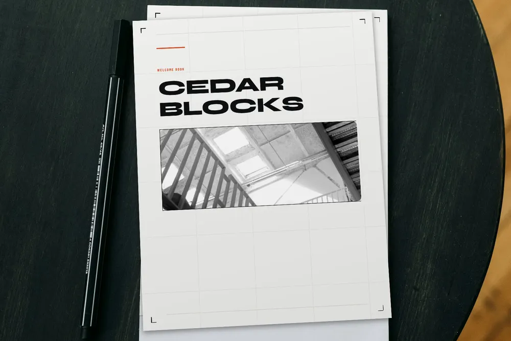 The printed Cedar Blocks Welcome Book, in the Urban Loft design, on a wooden table